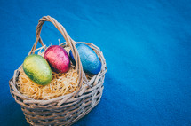 colored easter eggs in a wicker basket on a blue background