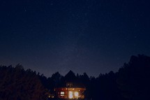 lights on in a cabin at night under stars in the night sky 
