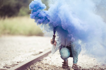 a woman holding blue smoke flare 
