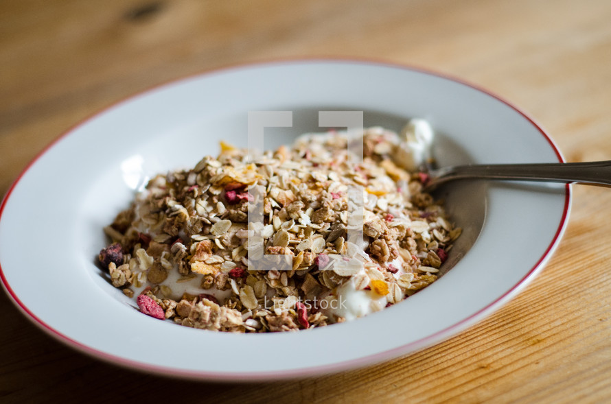 A bowl of museli / granola with a spoon on a wooden table