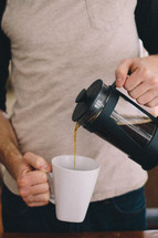 a man pouring coffee into a mug