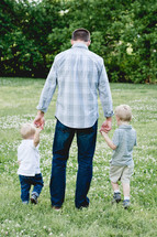 a father walking in a field with his sons 
