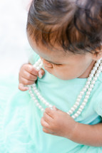 baby girl tugging on pearls 