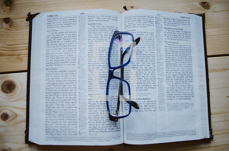 A pair of blue glasses sit atop an open bible