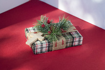 Small wrapped Christmas present with cross on red table