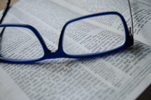 a pair of blue glasses sit atop an open bible, vision, 