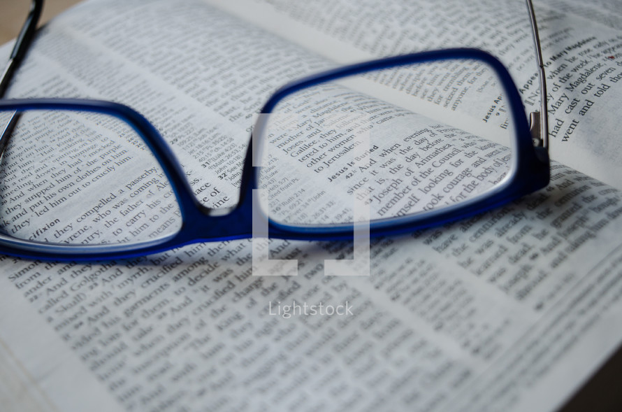 a pair of blue glasses sit atop an open bible, vision, 