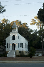 a small white church and steeple 