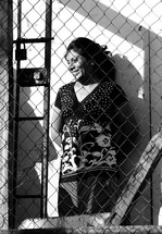 Woman standing behind locked fence