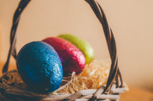 Colored easter eggs in a wicker basket on a table