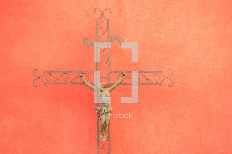 Iron crucifix against a textured orange wall