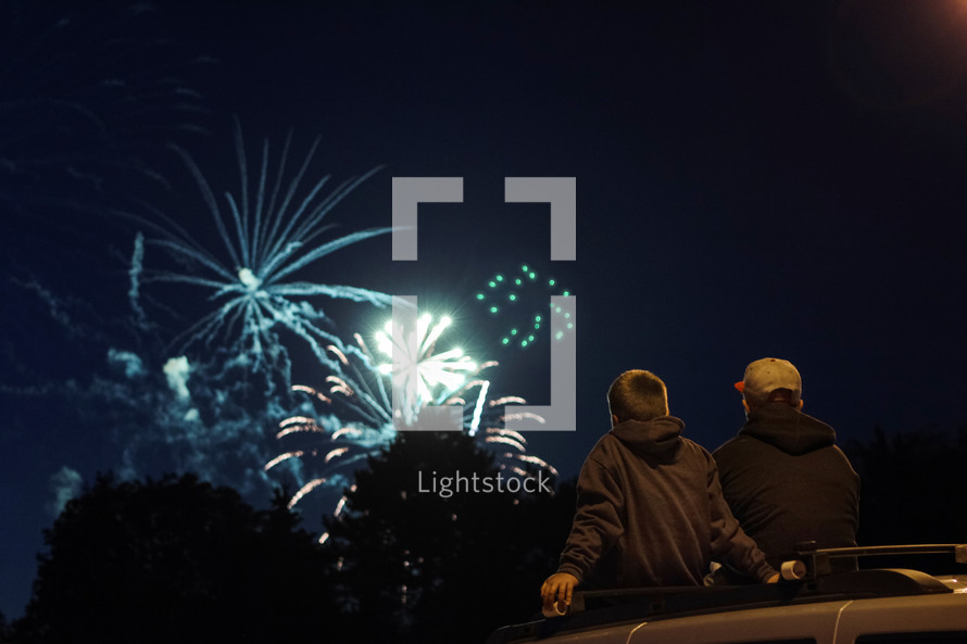 boys watching fireworks in the night sky 
