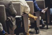 Close up of people's legs sitting in a church worship service.