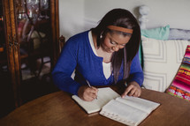 African-American woman reading a Bible and writing in a notebook 