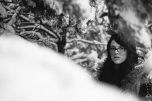 woman in glasses standing in a snow covered forest