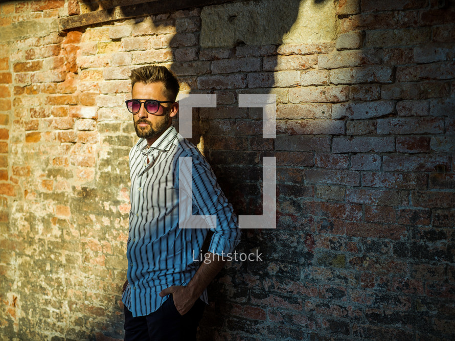 a man posing in front of a brick wall 
