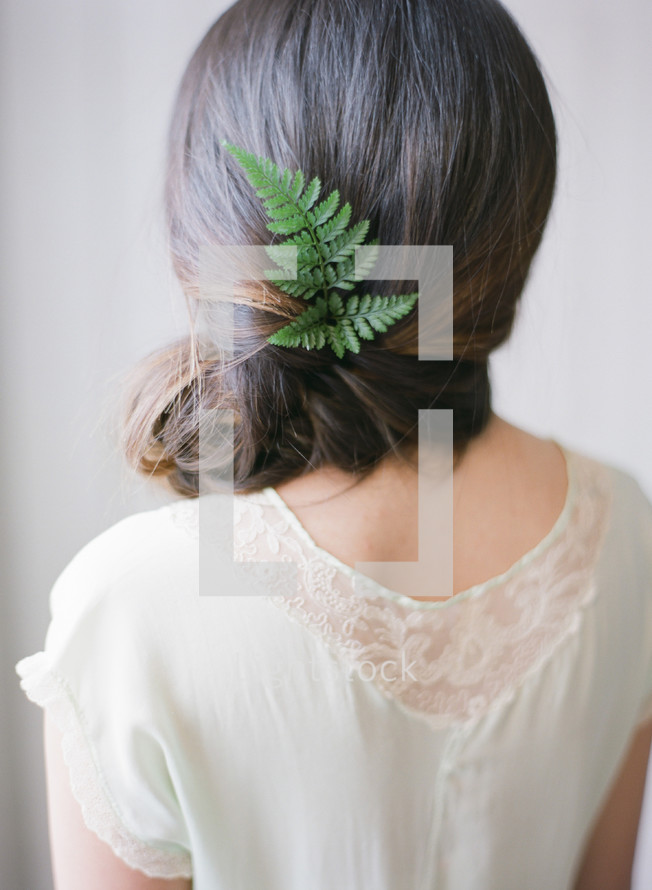 a woman with a fern twig in her hair 