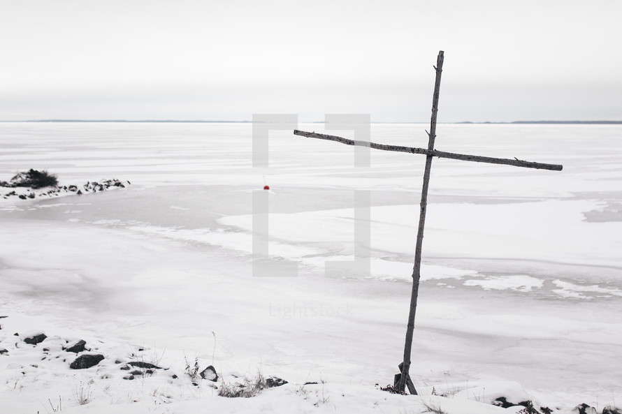 wooden cross by a frozen lake 