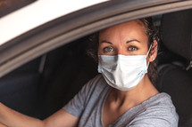 woman driving a car wearing a face mask 