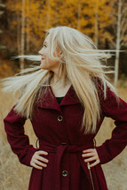 a young woman in a maroon coat standing outdoors 