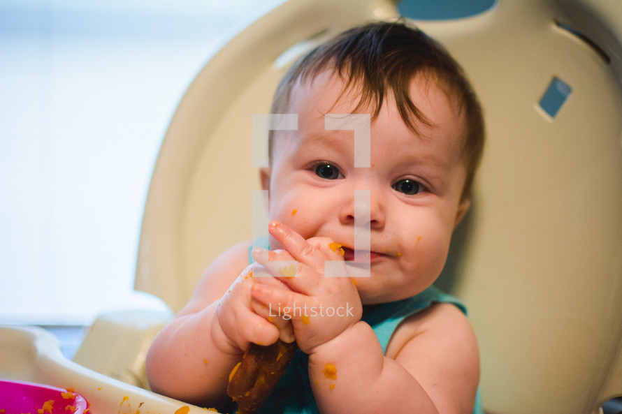 an infant eating baby food in a high chair 