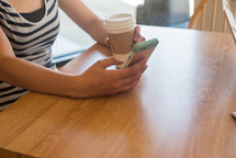 woman holding a coffee cup and texting 