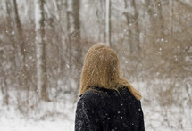 A woman standing outdoors in falling snow 