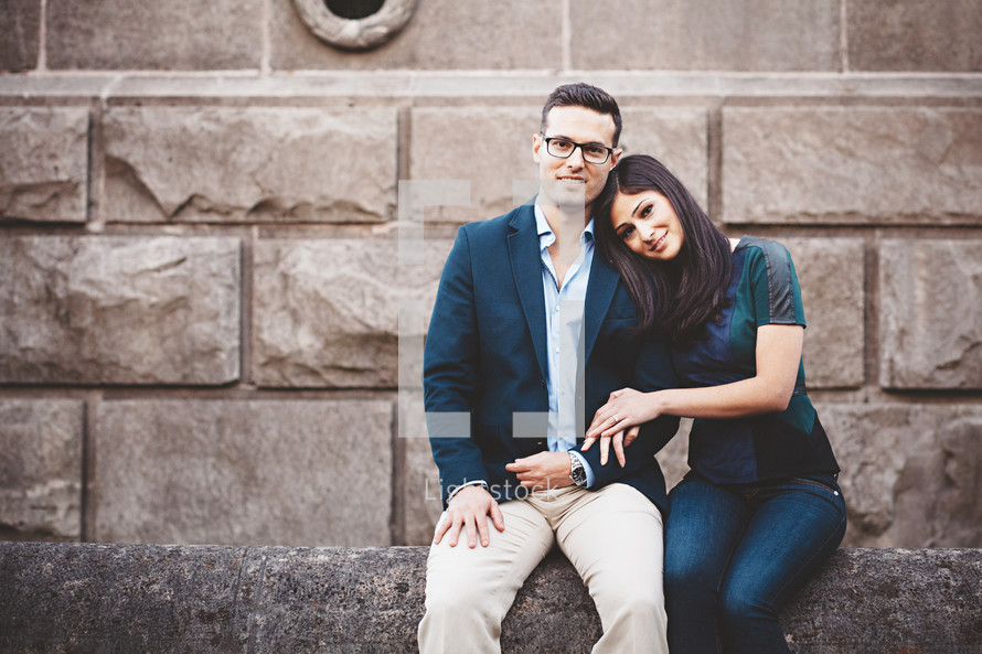 a couple sitting on a stone wall 