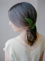 a woman with a fern twig in her hair 