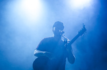 a man on stage singing into a microphone 