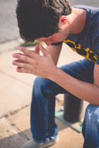 a teen boy with head bowed in prayer 