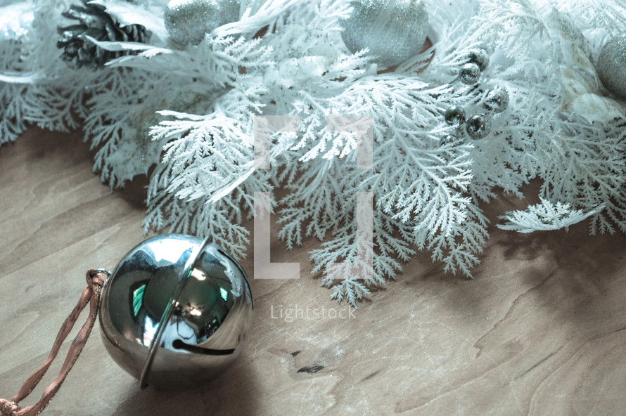 bell and white Christmas greenery on a wood background 