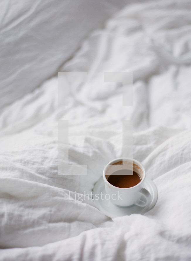 mug of cappuccino on a bed 