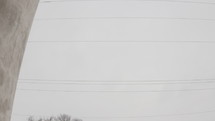 Drone flying quickly backward between the towers of a grain elevator in a wintry, overcast scene. D-Log