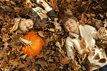 boys lying in a leaf pile 
