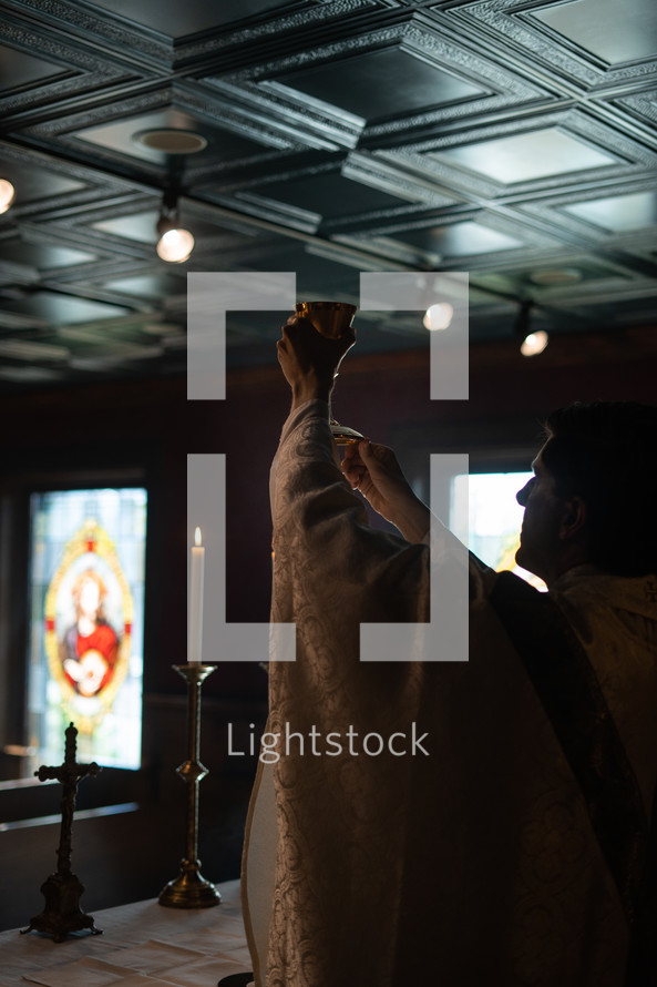 Communion chalice being raised up in a candle lit service. 