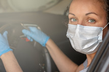 woman driving a car wearing a face mask 