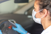 woman driving a car wearing a face mask and gloves 