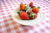 Fresh strawberries decorated on a straw hat. on a red picnic blanket.