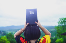 Happy little girl holding up Bible