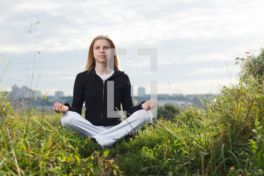 Young girl makes yoga exercises outdoors