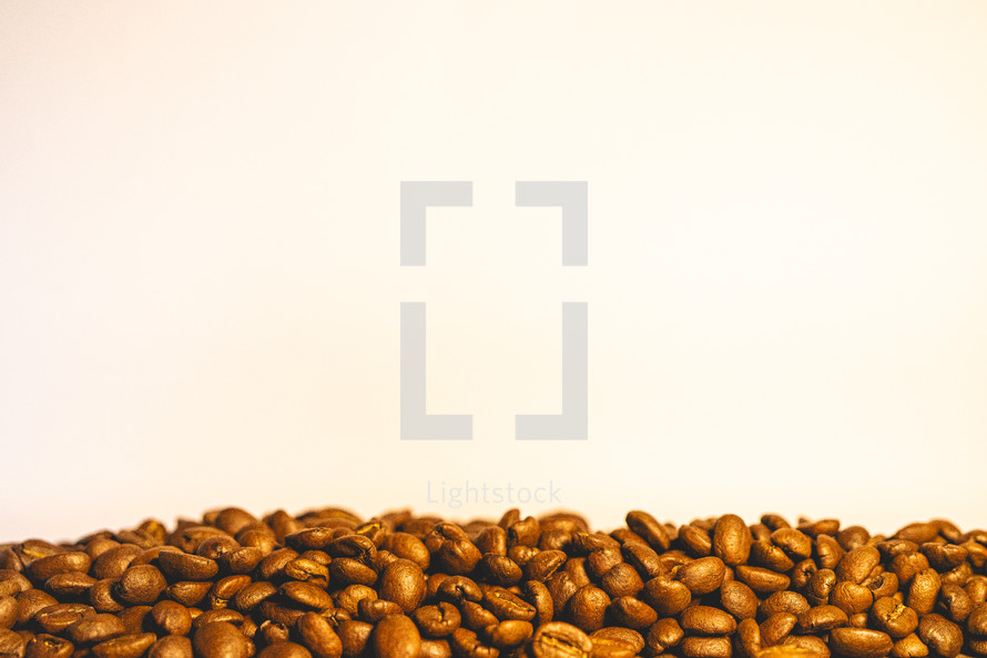 Bunch of coffee beans on a table with a light background.