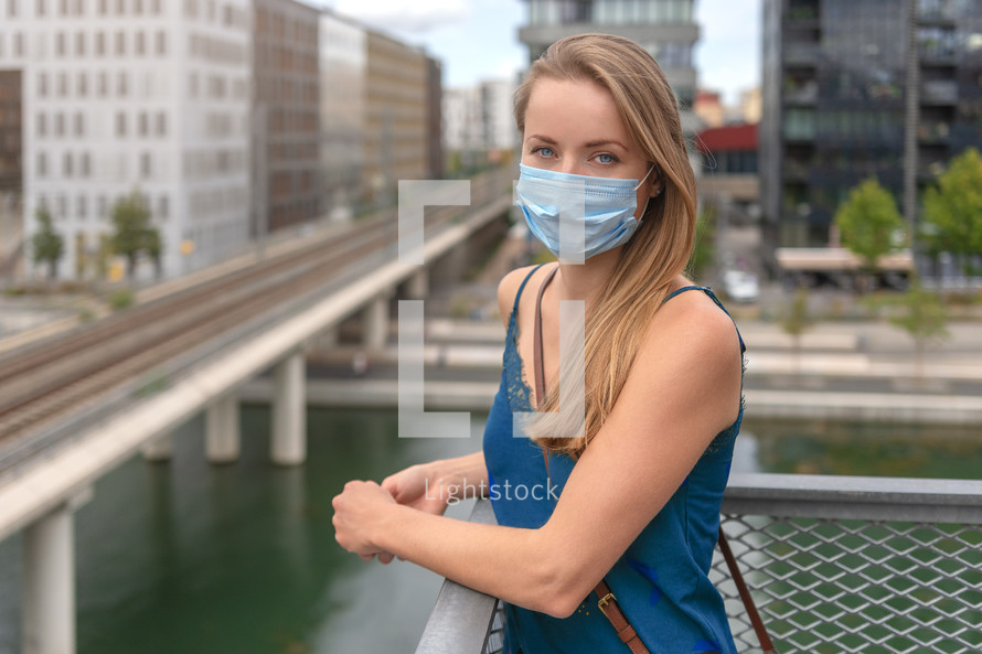 Urban city lifestyle. Young beautiful woman with face mask in modern residential district.