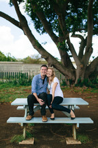 couple snuggling on a picnic table 