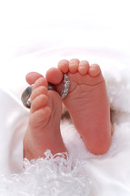 infant's feet with wedding bands around the toes