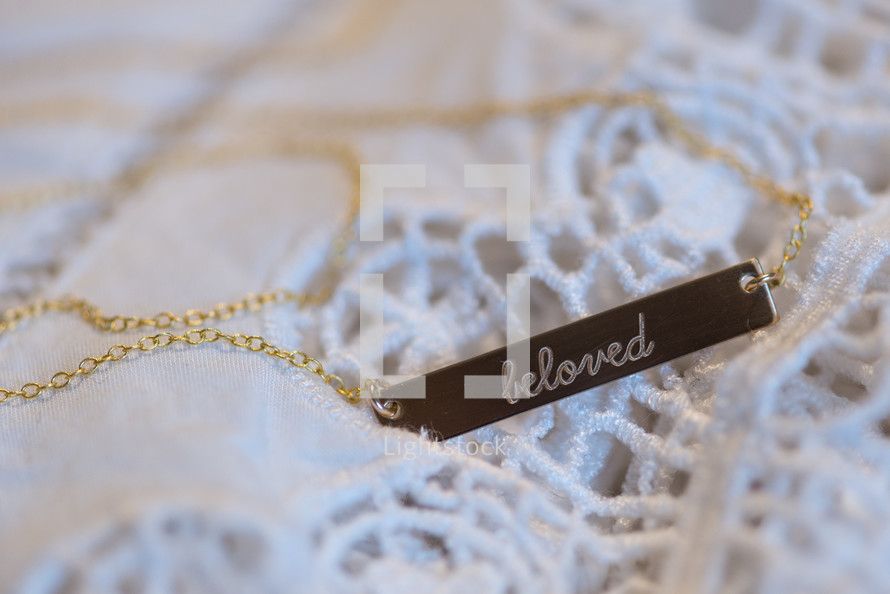 A necklace reading, "beloved," on a gold chain.