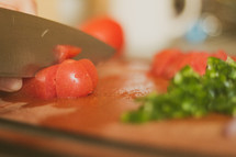 Chopping tomatoes and green peppers on a cutting board 