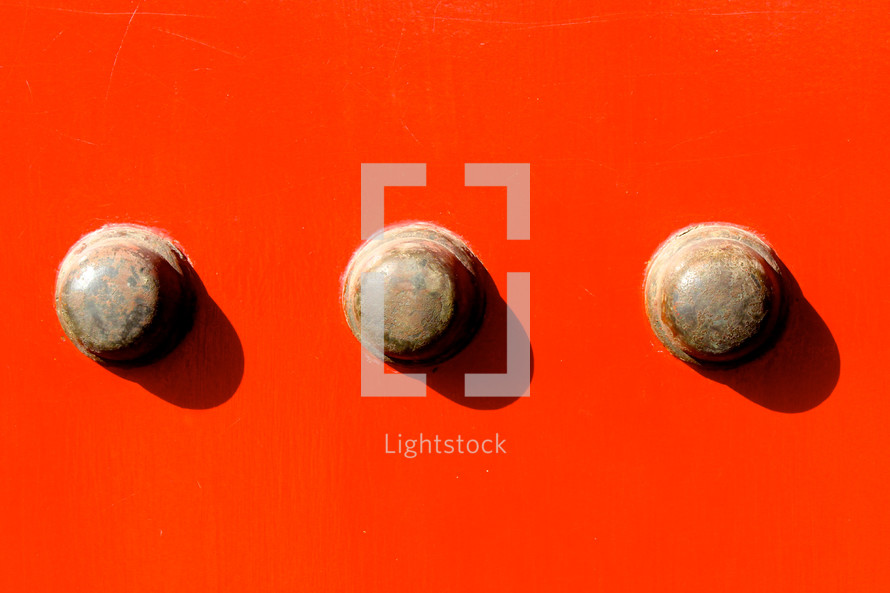 Doorknobs on a bright red wall.