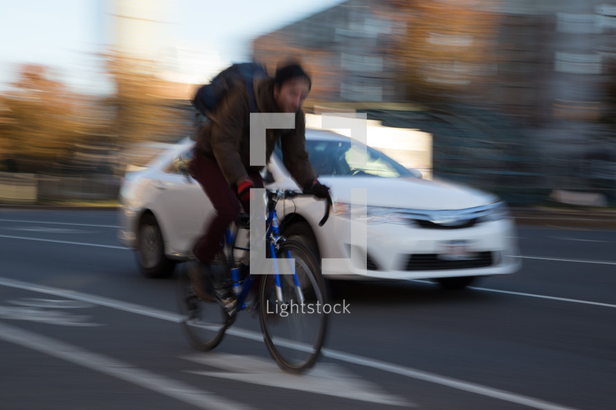 a man riding a bicycle on a road near passing cars 