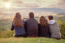 Christian worship and praise. Group of friends hugging outdoors at sunset.